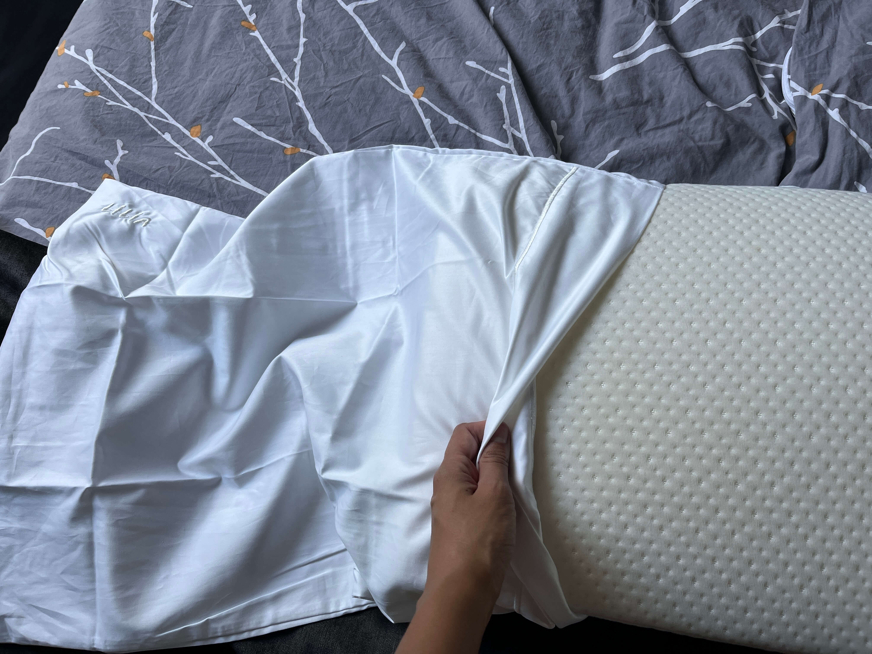 Pessoa a colocar fronha de algodão numa almofada